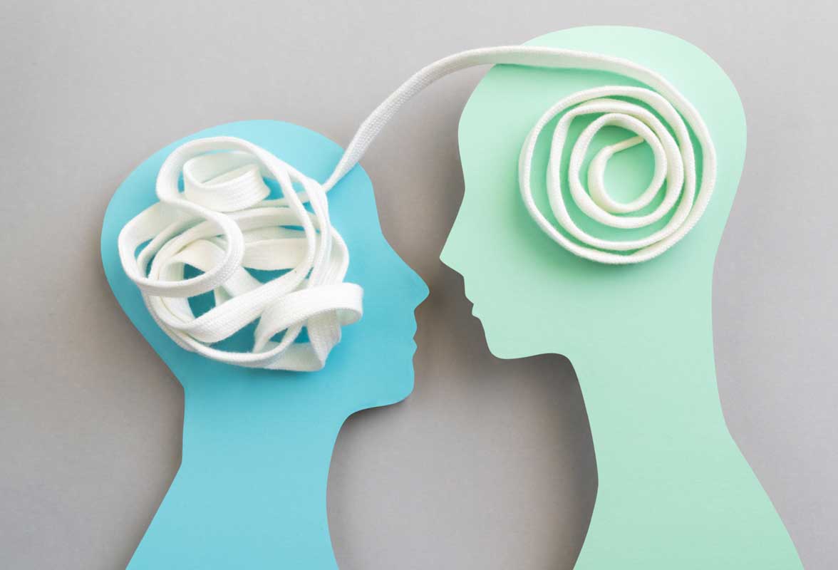 Le DNR : Une technique thérapeutique révolutionnaire pour reprogrammer le cerveau Deux silhouettes de têtes en papier, bleu et vert menthe, reliées par un lacet blanc représentant la pensée et la communication. Concept d'échanges d'idées ou de psychothérapie